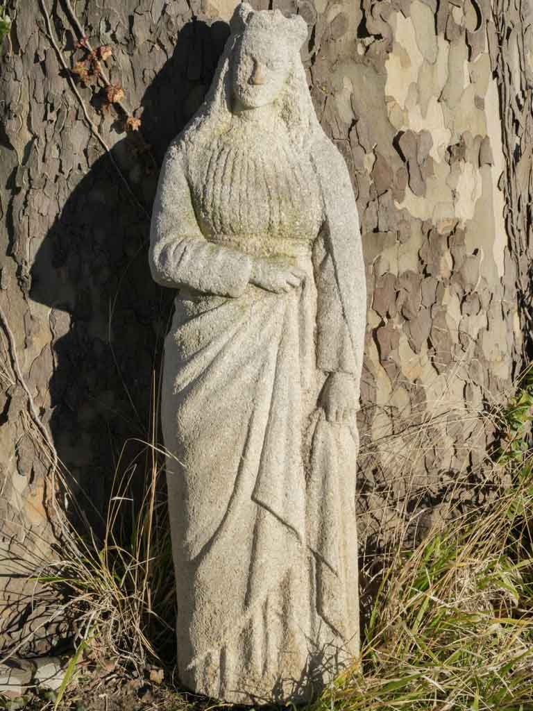 Aged stone maiden garden statue