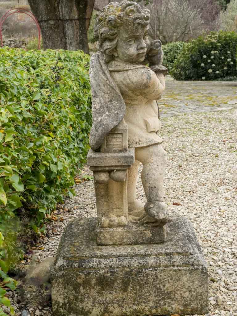 Weathered stone cherub garden statue