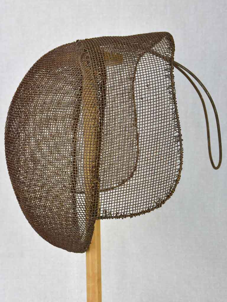 Collection of three antique French fencing masks on vintage hat stands