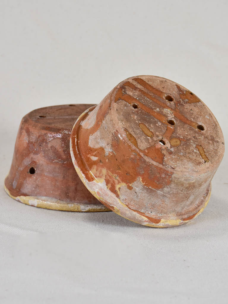 Two antique French clay cheese strainers with timeworn yellow glaze