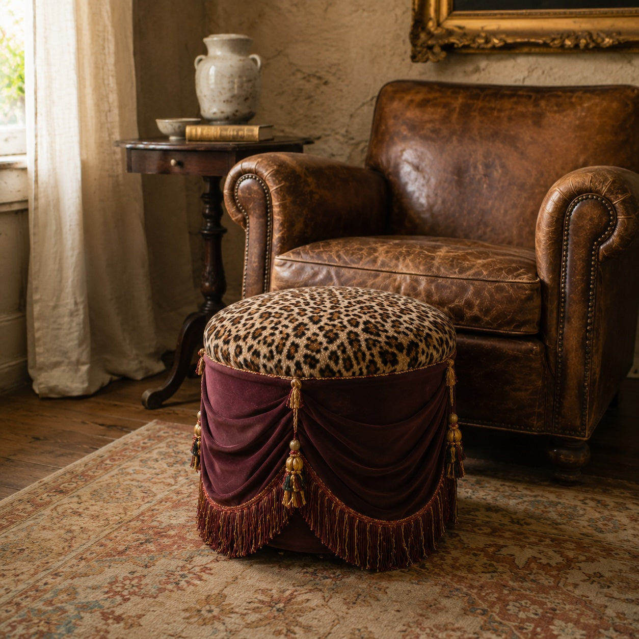 Antique French leopard upholstered pouf with plum tassel drapery beside a vintage leather club chair in a warm French interior