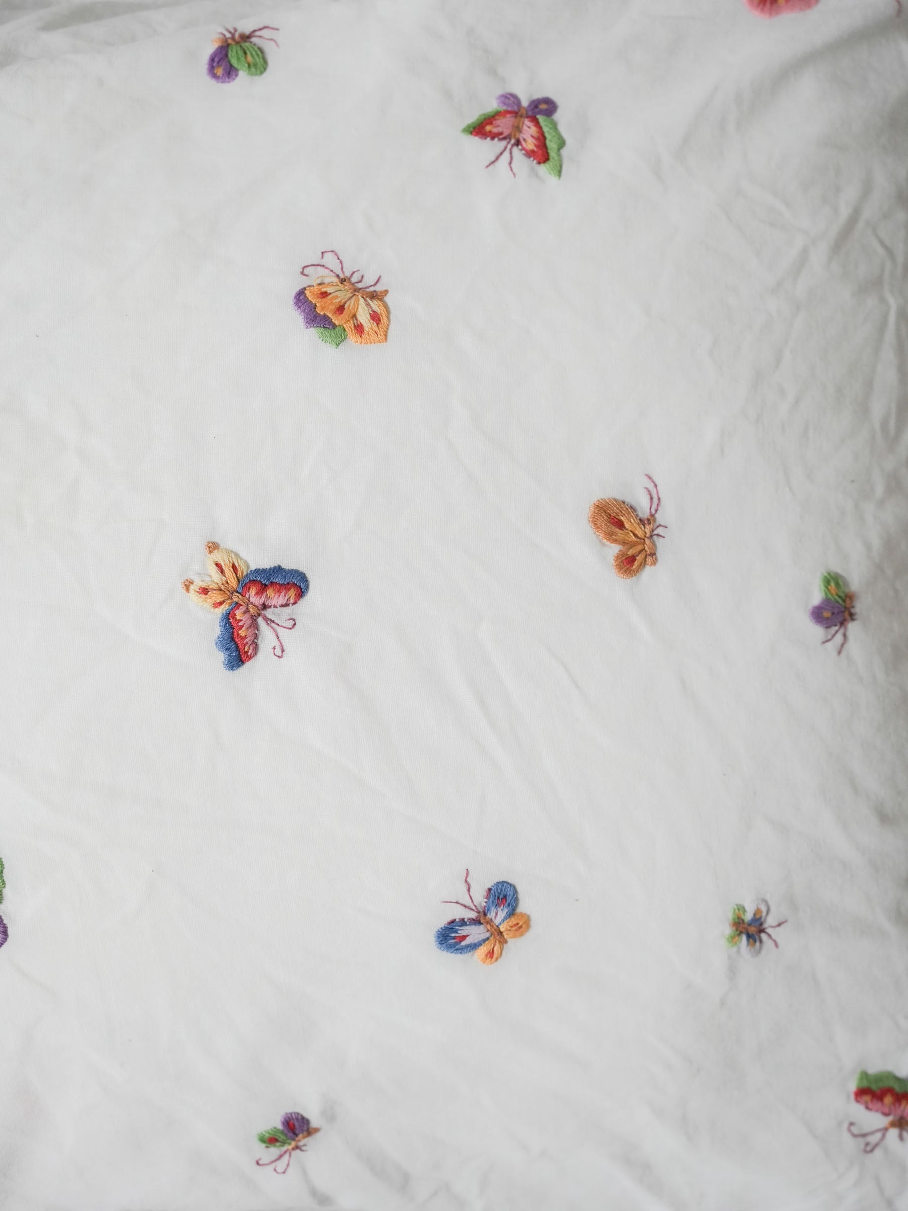 White pillowcase embroidered with colorful butterflies