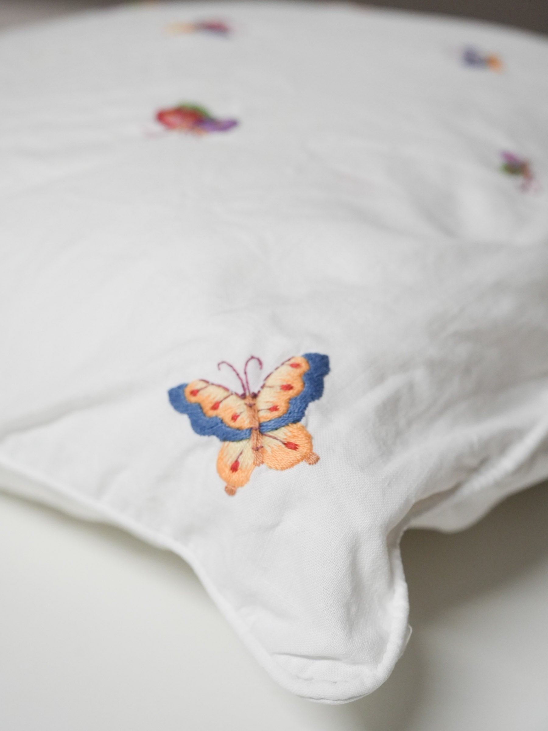 White pillowcase embroidered with colorful butterflies