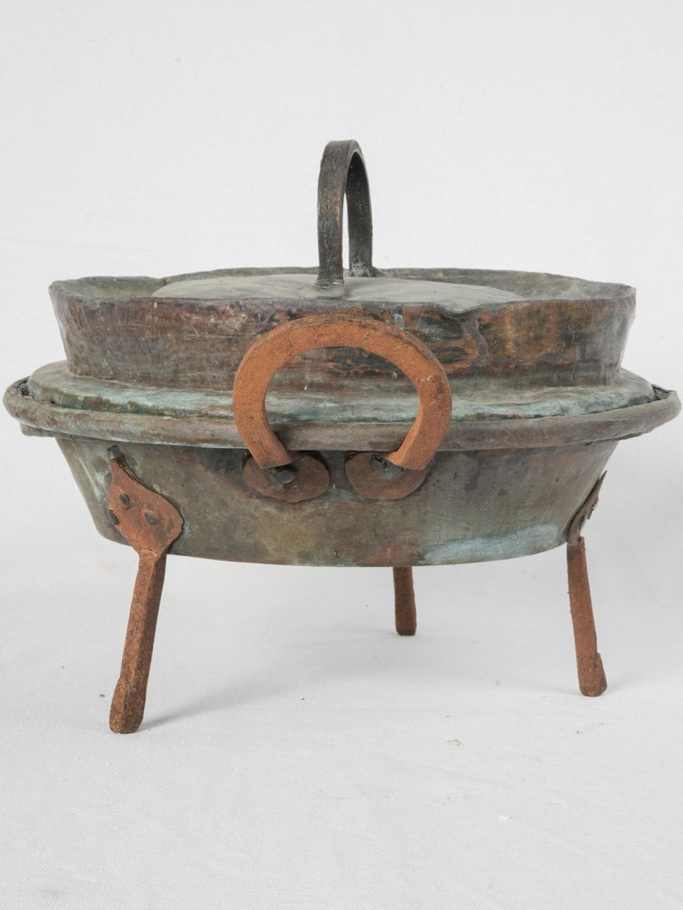 Rusted, iron-legged copper marmite pot