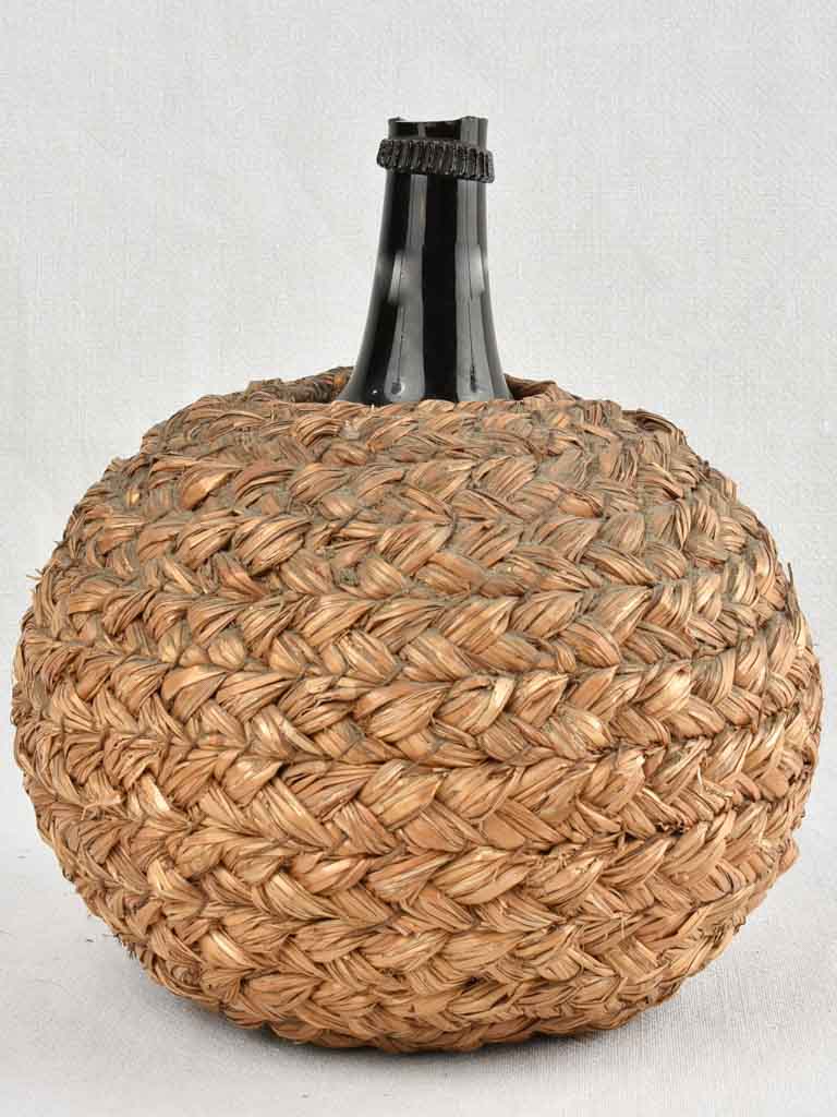 Small demijohn bottle in woven straw basket 12¼"