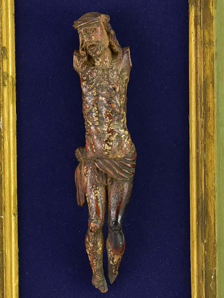 18th Century sculpted wooden Christ on blue fabric with a green and gold frame 11¾" x 18½"