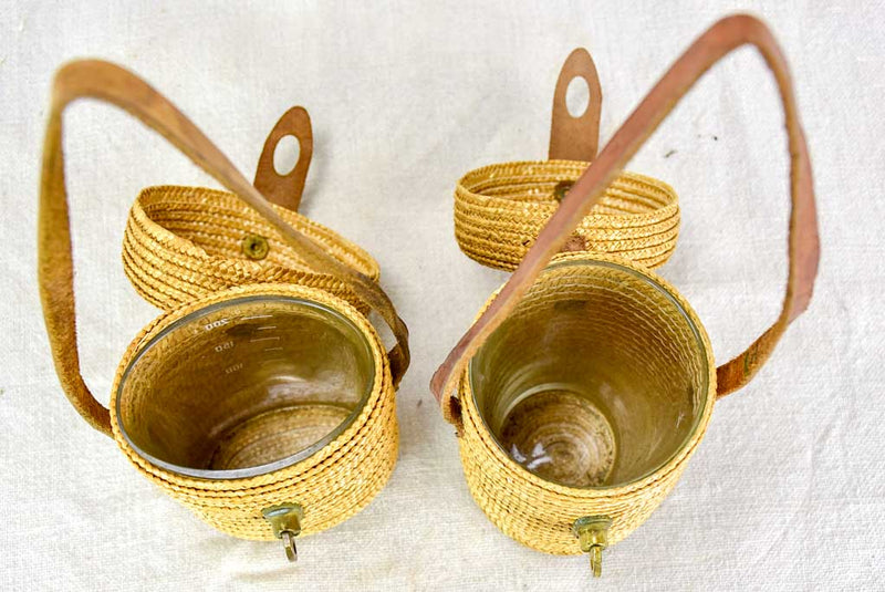 Two mid century French 'verre de cure' glasses in baskets