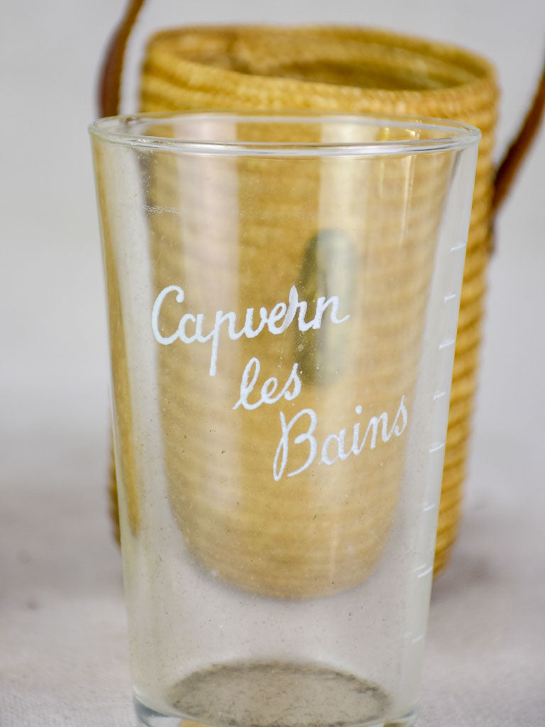 Two mid century French 'verre de cure' glasses in baskets