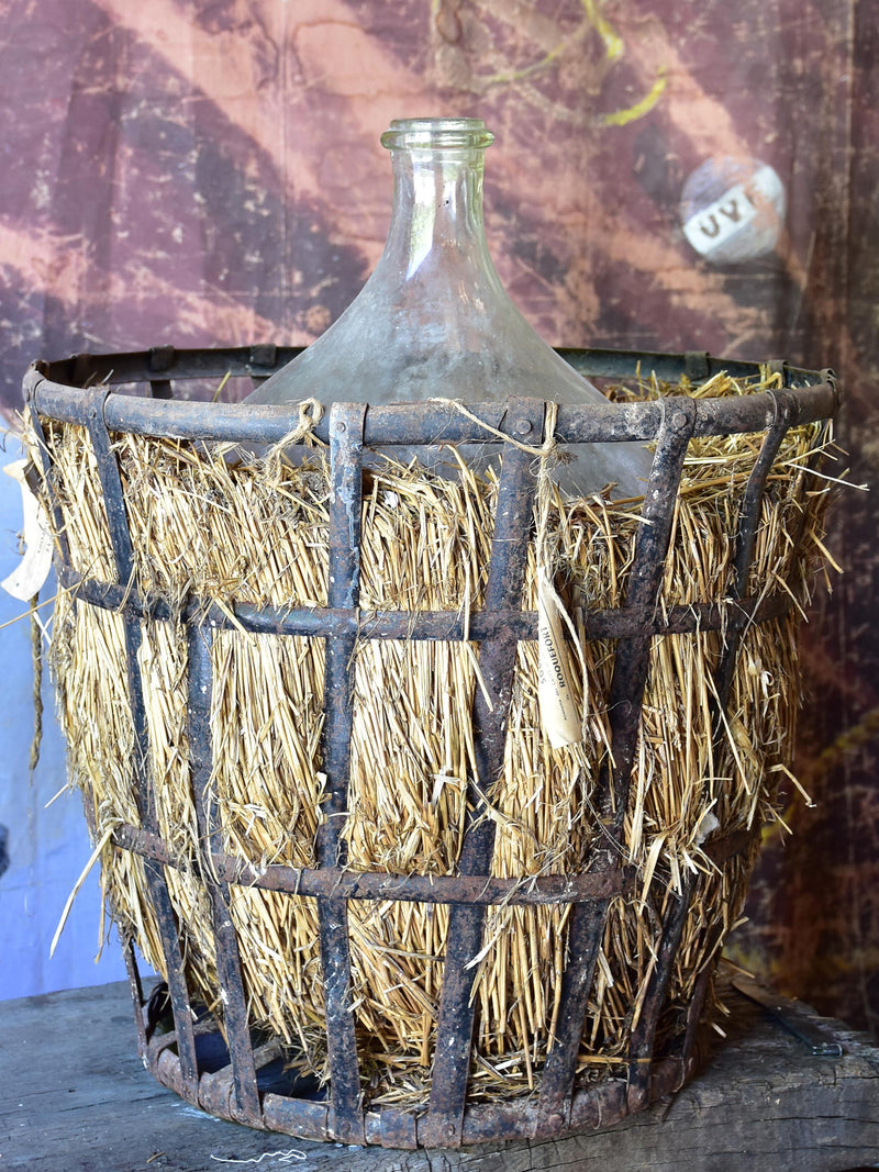 Very large antique French demijohn bottle in hay and crate