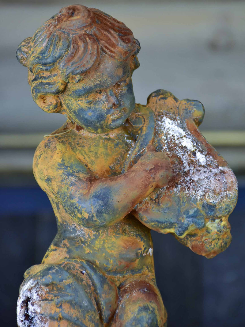 Two antique cast iron cherubs playing musical instruments