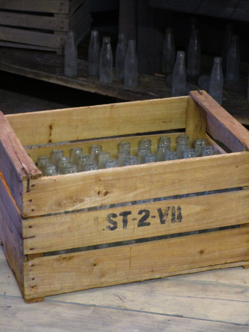 A rustic French fruit box filled with vintage glass bottles